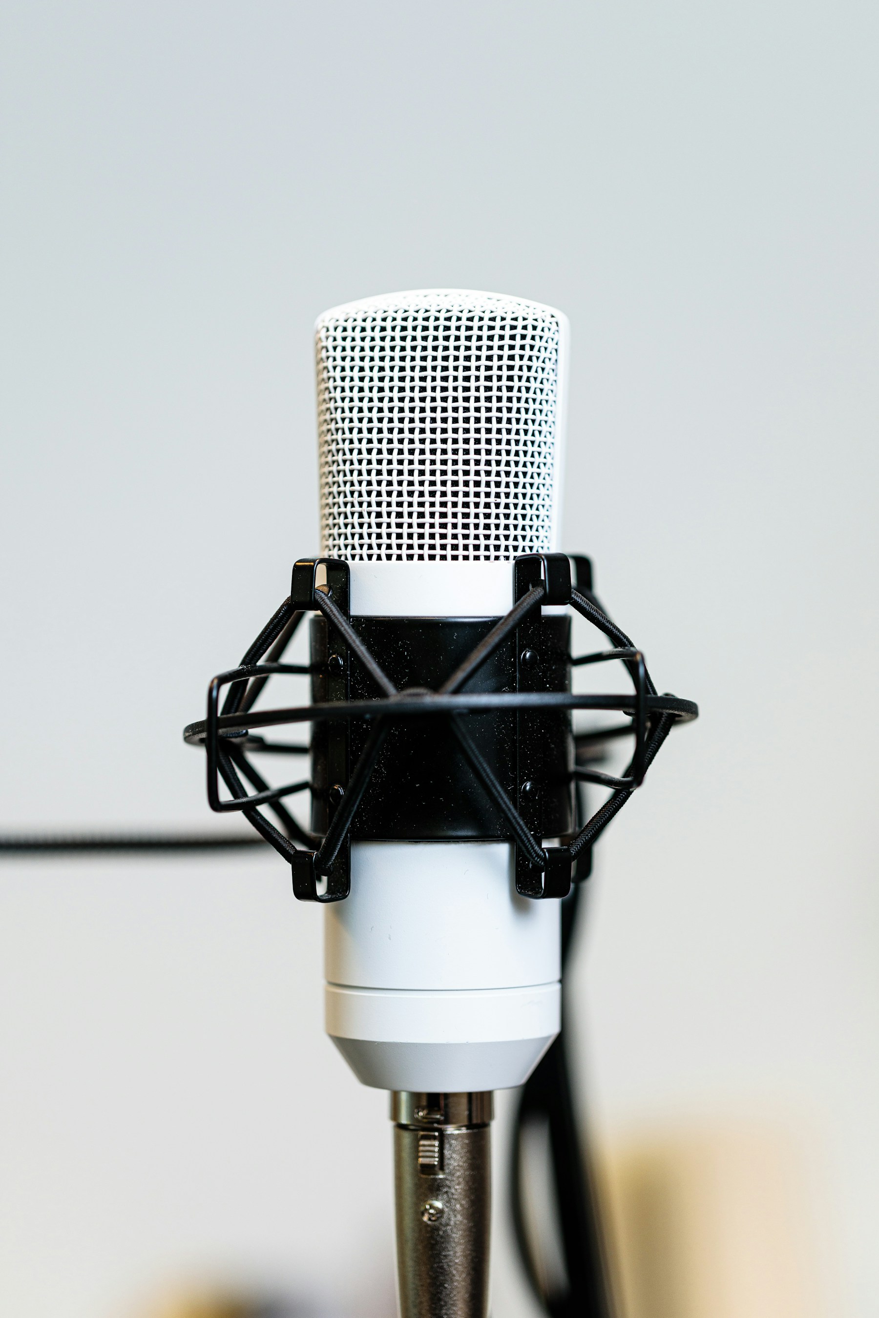 A silver studio microphone against a bright background